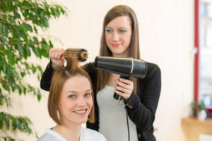 hairdresser making locks with barrel brush and blow-dryer
